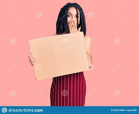 Cute African American Girl Holding Empty Banner Covering Mouth With Hand Shocked And Afraid For