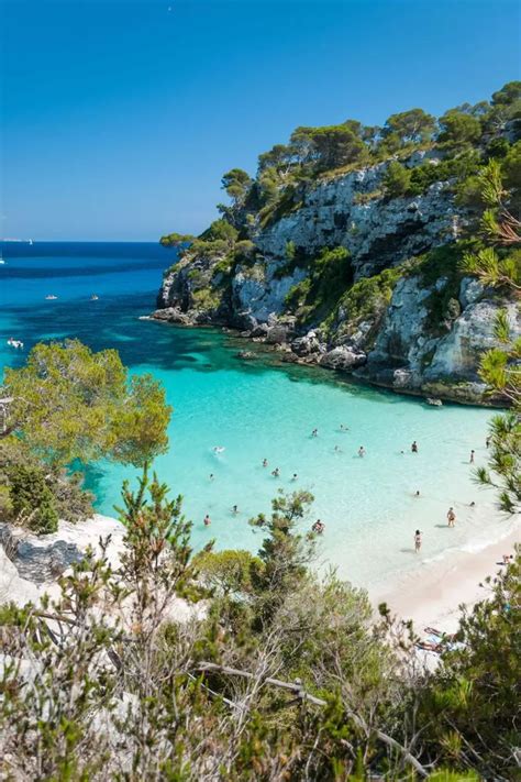 people are swimming in the clear blue water at an island with white sand and green trees