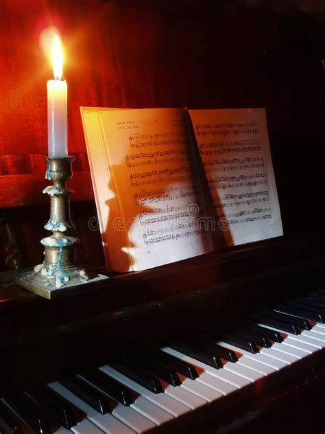 Piano and sheet music in the candle lighting. Piano and opened book ...