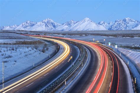 Red And Yellow Cars Trails On The Highway With Mountains On Horizon