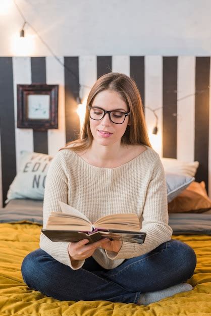 Mujer Joven Sonriente Que Se Sienta En El Libro De Lectura De La Cama