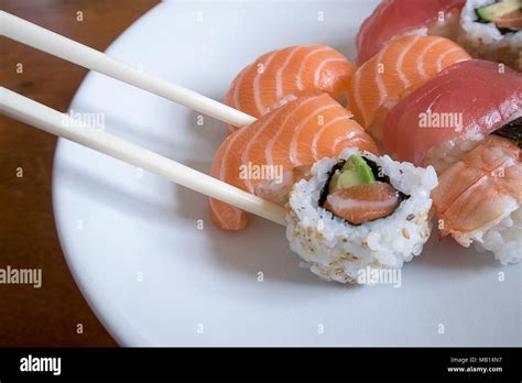 Fresh Salmon Nigiri Sushi Between Chopsticks Along With Uramaki Prawn