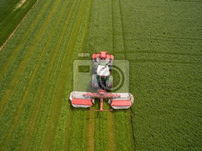 Z lotu ptaka ciągnik z przyczepą w pracy w polu złotego pszenicy