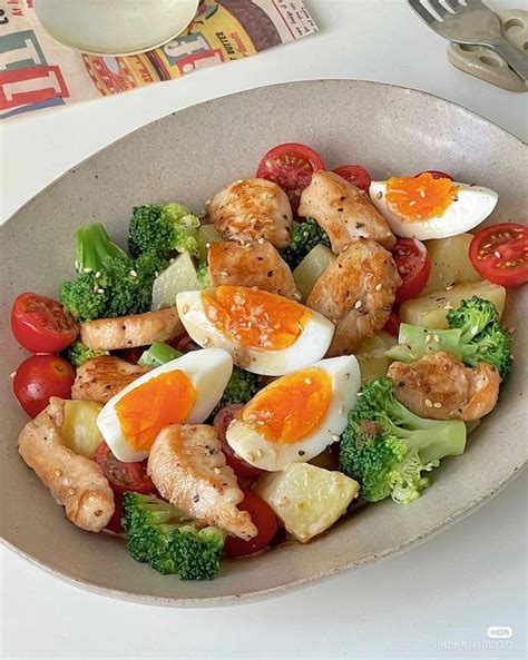 A Bowl Filled With Meat And Veggies On Top Of A Table Next To A Fork