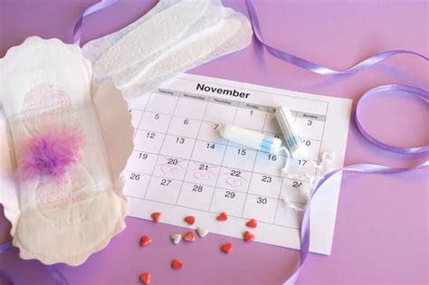 Menstrual Pads And Tampons On Menstruation Period Calendar Flat Lay On Lilac Background Stock