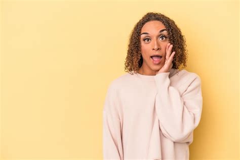 Jovem transexual latina isolada em fundo amarelo grita alto mantém os olhos abertos e as mãos