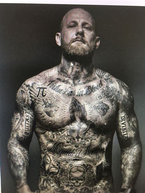 A Man With Lots Of Tattoos On His Body And Chest Standing In Front Of A Black Background