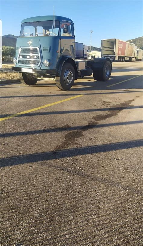 An Old Blue Truck Is Parked On The Side Of The Road With Other Trucks