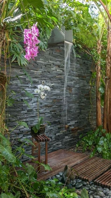 An Outdoor Shower Surrounded By Greenery And Flowers In A Backyard Area