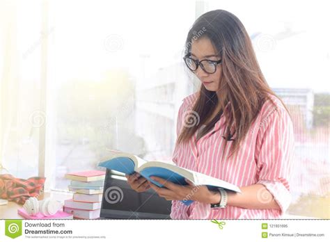 Beautiful Young Woman Reading A Book To Find Out Information In The