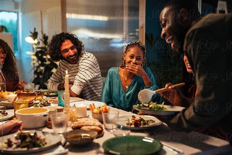 Friends Laughing While Serving Food By Stocksy Contributor