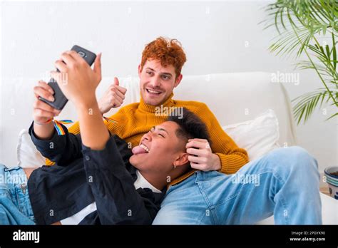 Beautiful Gay Couple Being Romantic Indoors On The Sofa Gay Couple Taking A Selfie Stock Photo
