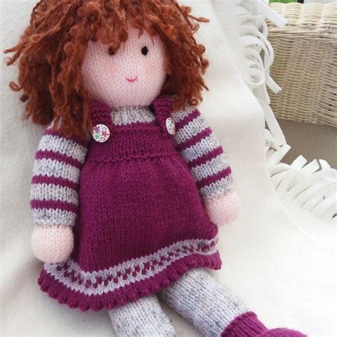 A Knitted Doll With Red Hair Wearing A Purple Dress And Striped Socks