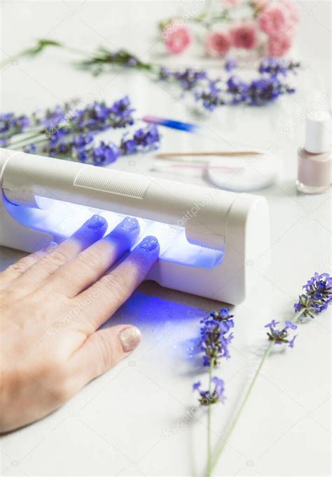 Primer plano de la mano de la mujer usando led UV luz lámpara secador