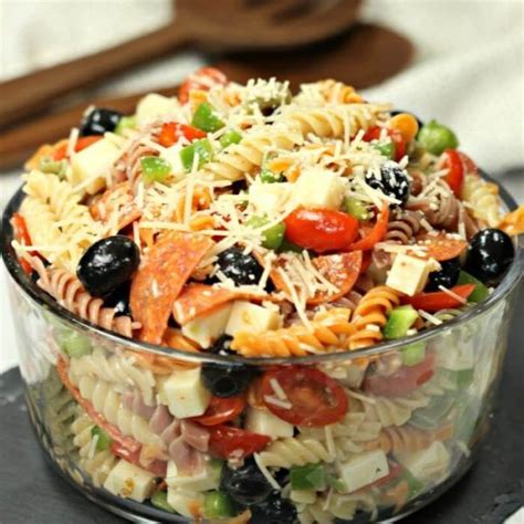 A Glass Bowl Filled With Pasta Salad On Top Of A Table