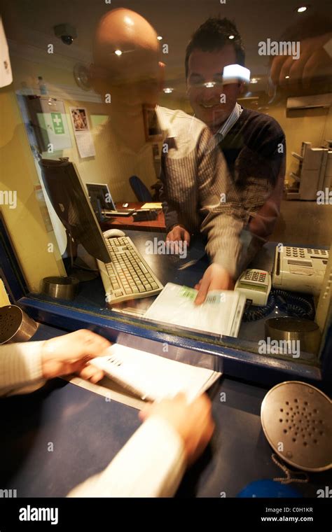 Man Passing Documents Through Counter Window Stock Photo Alamy