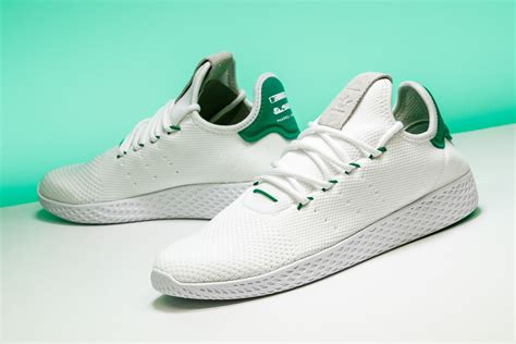 A Pair Of White Tennis Shoes With Green Accents On The Upper Part Of