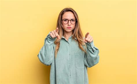 Mulher Bonita Caucasiana Apontando Para A Câmera Com Os Dois Dedos E Uma Expressão De Raiva