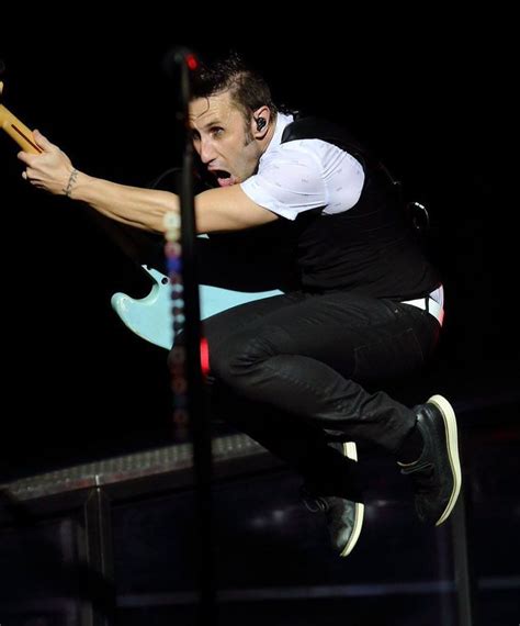 A Man Is Jumping In The Air With His Guitar