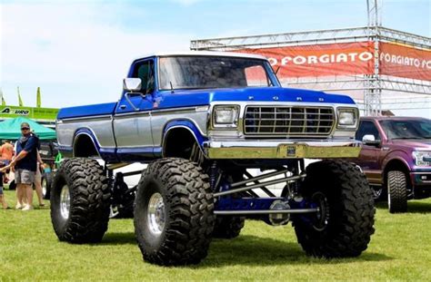 A Large Blue Truck Parked On Top Of A Lush Green Field