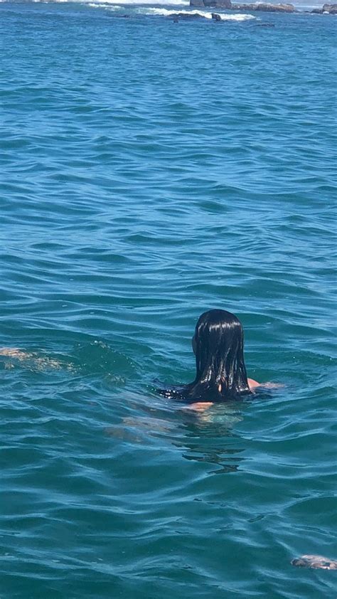 A Woman Swimming In The Ocean With Her Head Above Water