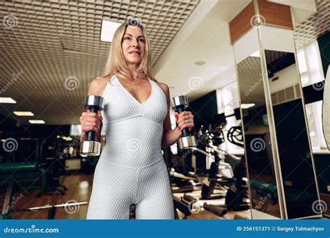 Sporty Middle Aged Blonde Woman Lifting Dumbbells In A Gym Stock Image