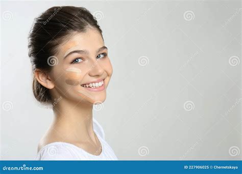 Beautiful Girl On Light Grey Background Using Concealers And Foundation For Face Contouring