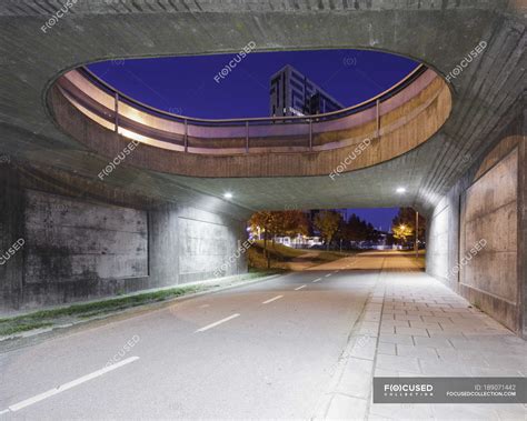 Road Under Bridge With Buildings In Background — Outdoors Horizontal