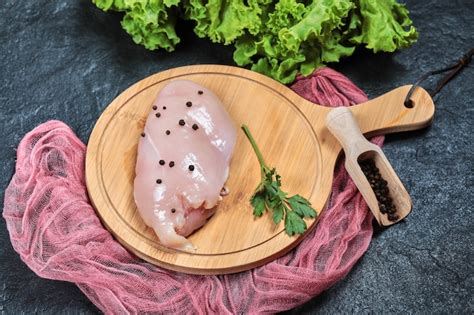 Free Photo Raw Chicken Fillet On Wooden Board With Greens And Tablecloth