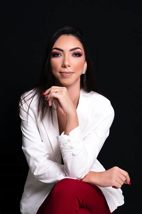 A Woman Sitting On Top Of A Chair Wearing Red Pants And A White Blazer