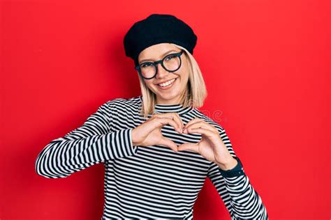 Beautiful Blonde Woman Wearing French Look With Beret An Glasses Smiling In Love Showing Heart