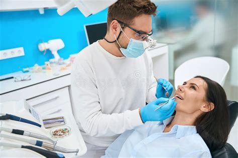 Male Orthodontist Using Teeth Prosthesis And Sickle Probe To Show