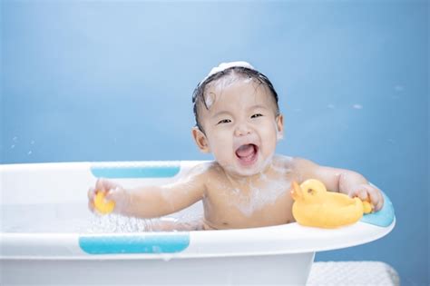 Premium Photo | Baby having bath in tub and playing with Yellow Duck on ...