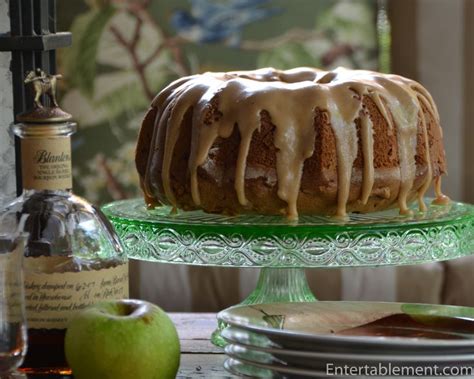 A Bundt Cake With Icing Sitting On Top Of A Glass Platter Next To Plates