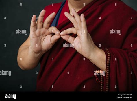 Closeup Of Hands Of Crop Praying Tibetan Monk In Traditional Red Robe