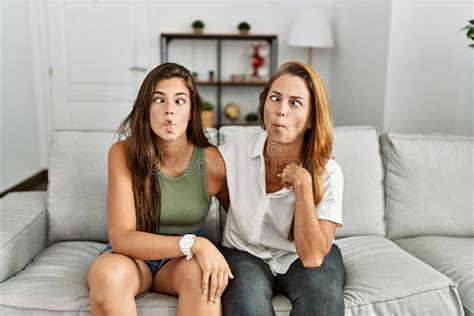 Mother And Daughter Together Sitting On The Sofa At Home Making Fish