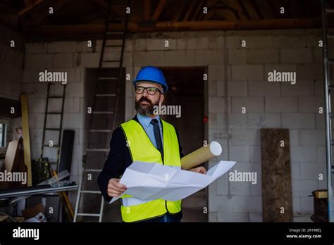 Mature Businessman Controlling Blueprints From Unfinished House Stock
