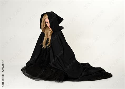 Full Length Portrait Of Blonde Girl Wearing Long Black Flowing Cloak