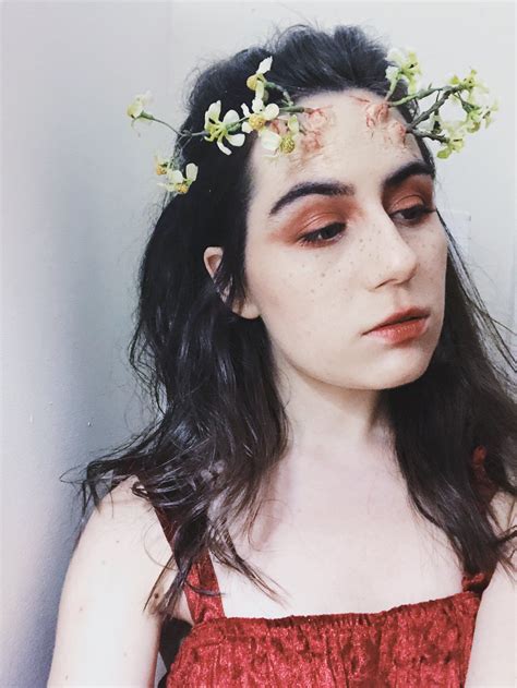 A Woman With Flowers In Her Hair Wearing A Red Dress And Holding A Cell