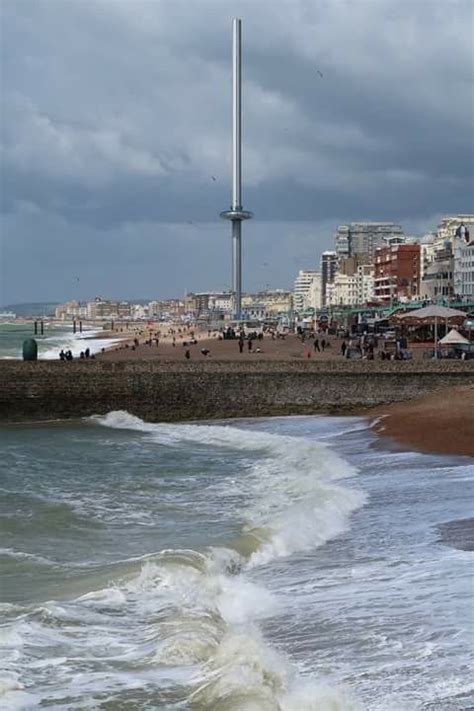 The Beach Is Crowded With People And Umbrellas On A Cloudy Day In This City