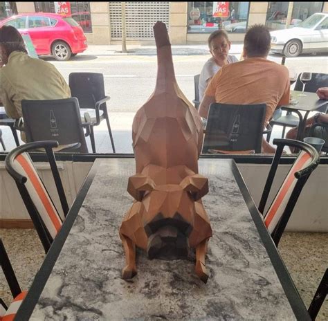 A Wooden Animal Sculpture Sitting On Top Of A Table Next To Two People