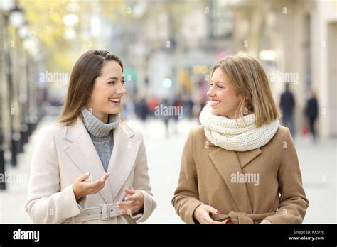 Front View Portrait Of Two Women Friends Wearing Coats Talking And