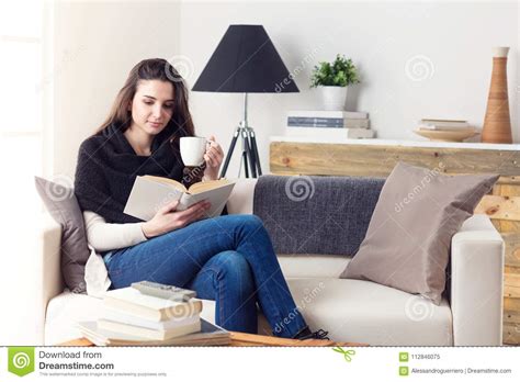 Woman Reading A Book Sitting On A Couch At Home Stock Image Image Of