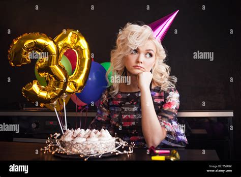 Anniversaire anniversaire Jeune belle blonde assise devant un gâteau d anniversaire et triste