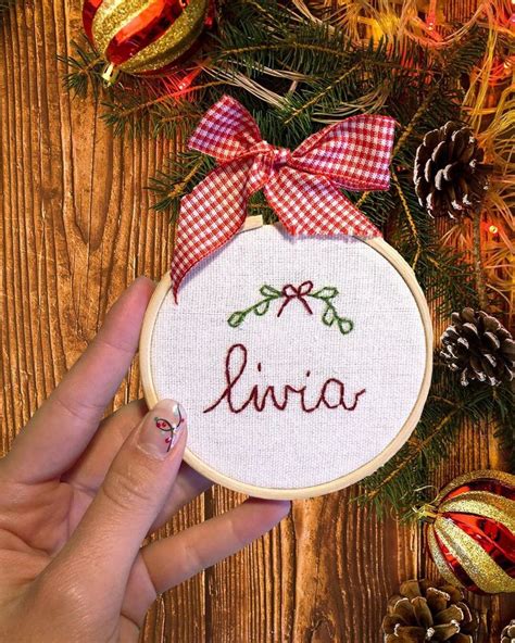 Someone Holding Up A Cross Stitch Ornament With The Word Livvia On It