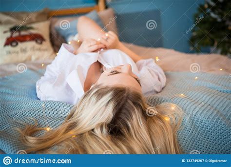 Une Jeune Fille Blonde Dans Une Longue Chemise Masculine Blanche Se Trouvant Sur Le Lit Jetant