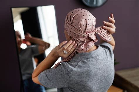 Back View Of Unrecognizable Bald Woman Tying Headscarf Stock Photo