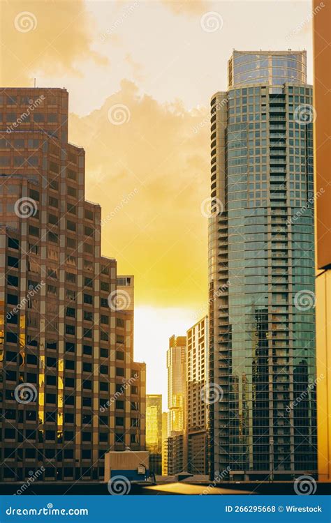 Vertical Aerial View Of Modern Glass Buildings Against Bright Yellow Sunset Sky Background In