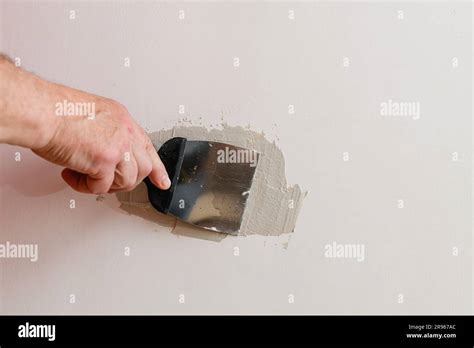 Repairing Holes In Drywall A Handyman Is Repairing A Hole In The