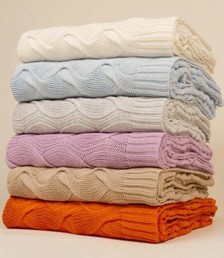 A Stack Of Folded Sweaters And Blankets On Top Of Each Other In Various